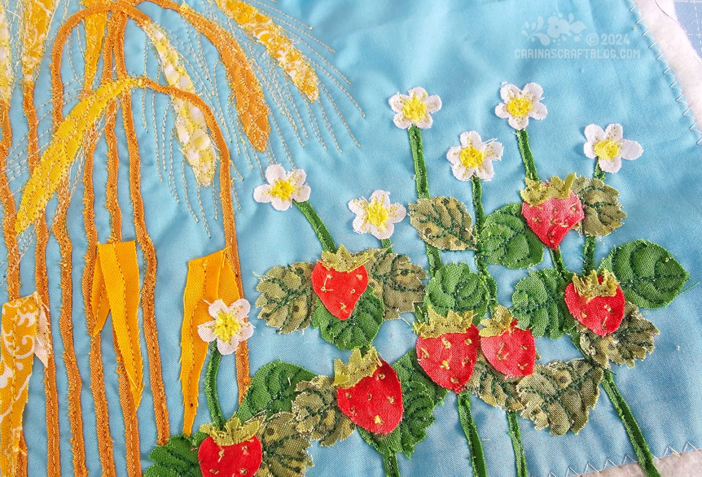 Detail photo of a strawberry plant appliquéd on a blue background.