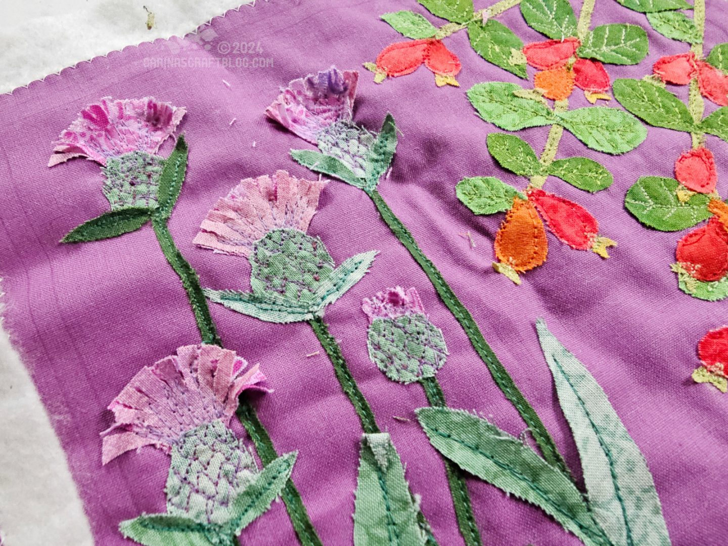 Close view of a fabric square with appliqué of common knapweed and rosehips.