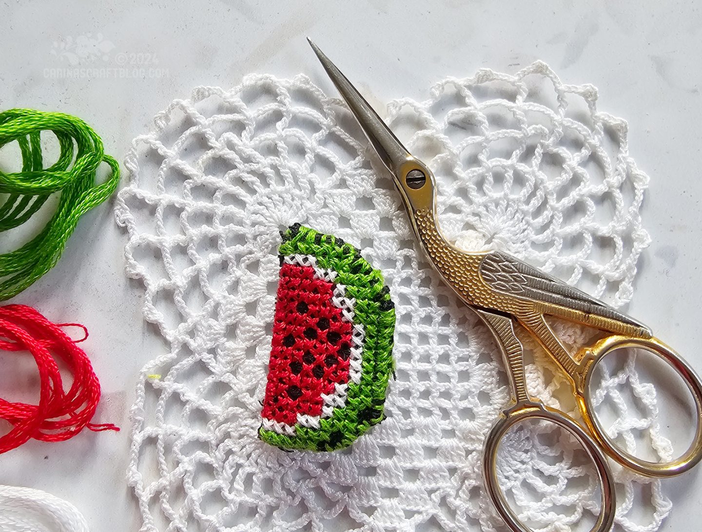 Photo of a small cross stitched brooch in the shape of a watermelon slice.