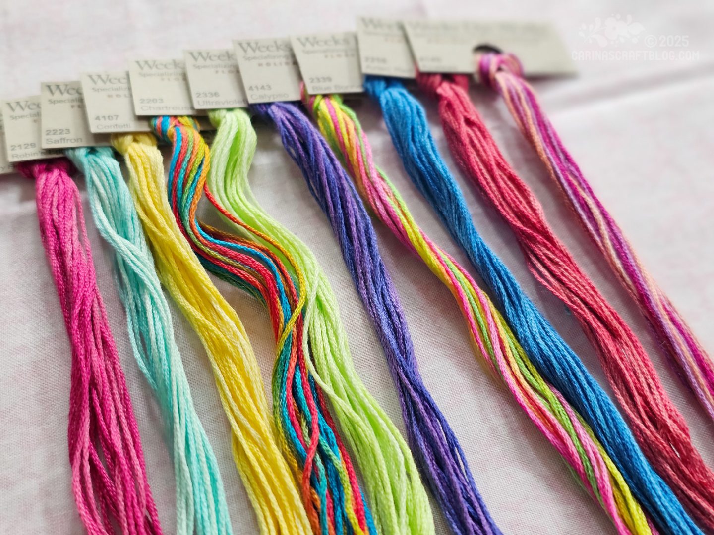 Photo. Overhead view of skeins of colourful embroidery thread laid out next to each other.